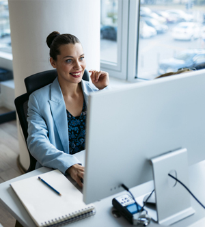 Cardinal woman smiling at desktop in office
